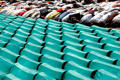 Menschen beten vor Särgen der Opfer von Srebrenicamassaker