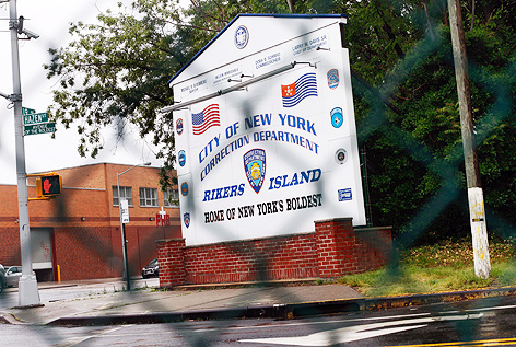 Eingangsschild von Rikers Island hinter einem Maschendrahtzaun fotografiert