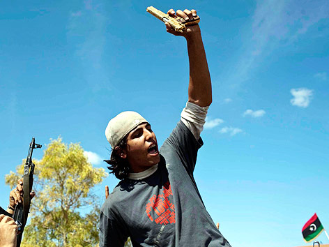 Ein Kämpfer der libyschen Übergangsregierung hält eine goldene Pistole in die Luft.