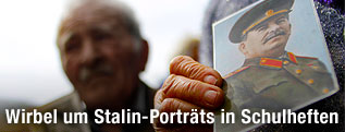 Frau hält ein Portraitbild von Josef Stalin