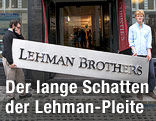 Zwei Arbeiter tragen ein "Lehman Brothers"-Schild