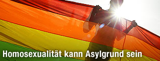 Person hinter einer Regenbogen-Flagge