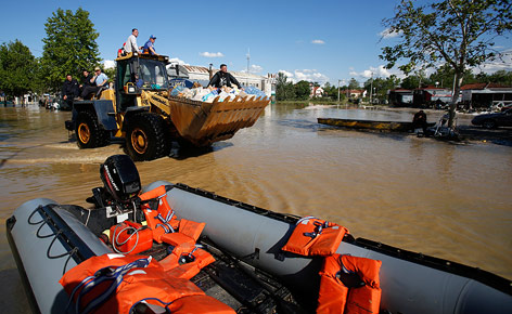 Männer fahren auf einem Bulldozer durch überflutetes Gebiet