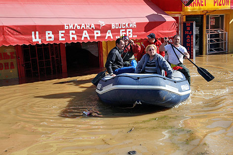 Personen fahren in einem Schlauchboot durch die überflutete serbische Ortschaft Obrenovac