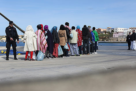 Flüchtlinge im Hafen von Lampedusa erhalten Anweisungen von Beamten