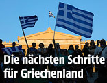 Menschen schwingen griechische Fahnen vor dem Parlament in Athen