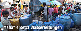 Menschen füllen Wasser von einem Tankwagen in Kanister