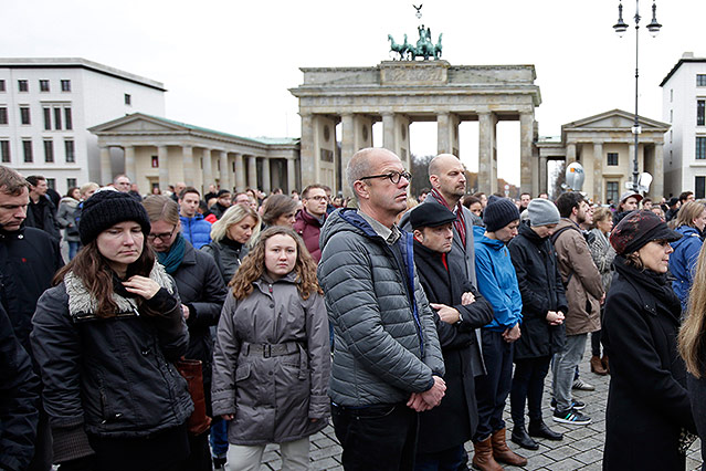 Menschen bei einer Gedenkminute am Brandenburger Tor in Berlin
