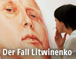 Frau blickt auf ein an eine Hauswand gemaltes Porträt des russischen Agenten Alexander Litwinenko