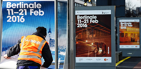 Ein Mann hängt Berlinale-Plakate in Berlin auf