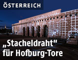 Lichtinstallation projeziert Stacheldraht auf die Tore der Hofburg