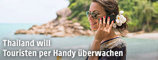 Eine Frau mit Mobiltelefon an einem thailändischen Strand