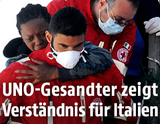 Mitarbeiter des italienischen Roten Kreuz' tragen einen Menschen von einem Rettungsboot