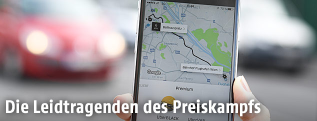 Uber-App auf einem Smartphone mit Autos im Hintergrund
